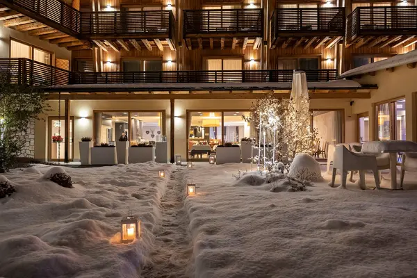 Cortile dell'hotel di sera illuminato da lanterne con neve e vista sulla sala interna
