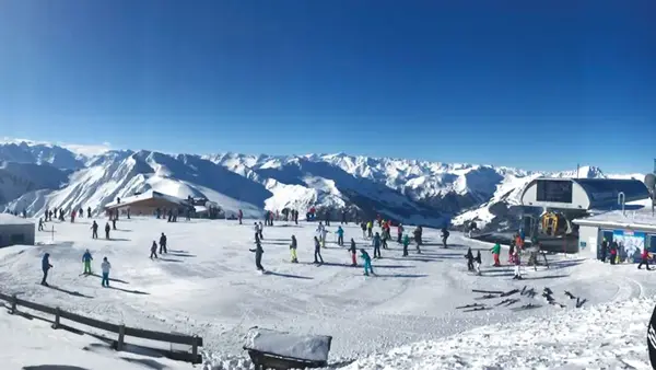 Comprensorio sciistico con sciatori sulla neve e panorama di cime alpine innevate