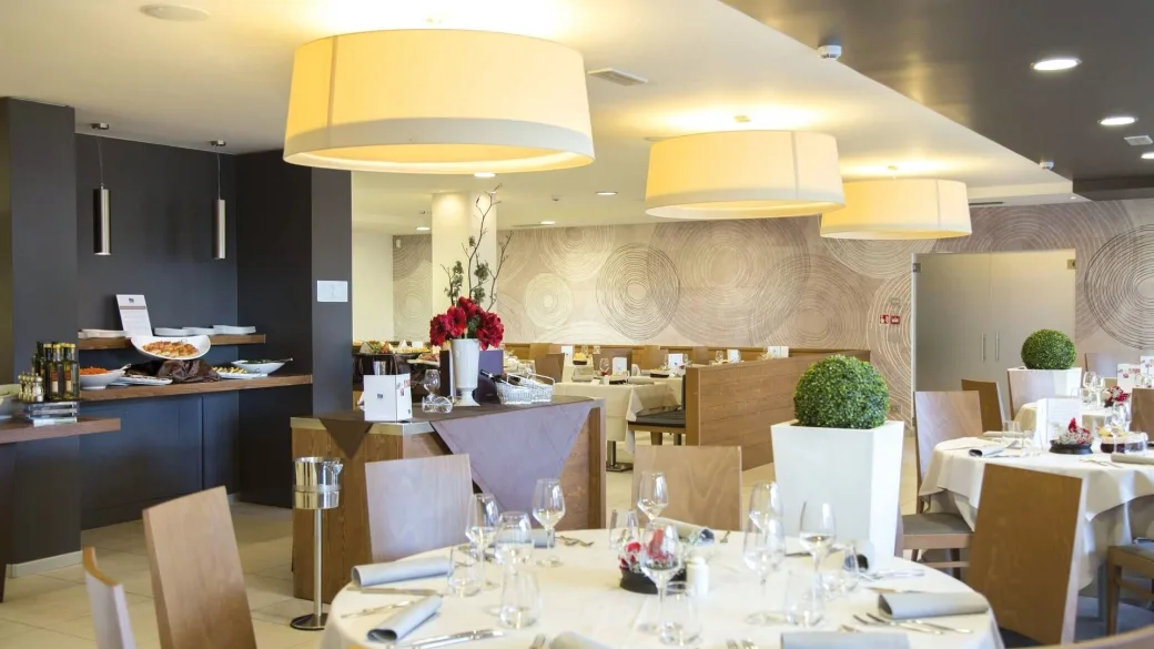 Sala ristorante elegante con tavoli apparecchiati, lampadari moderni e angolo buffet