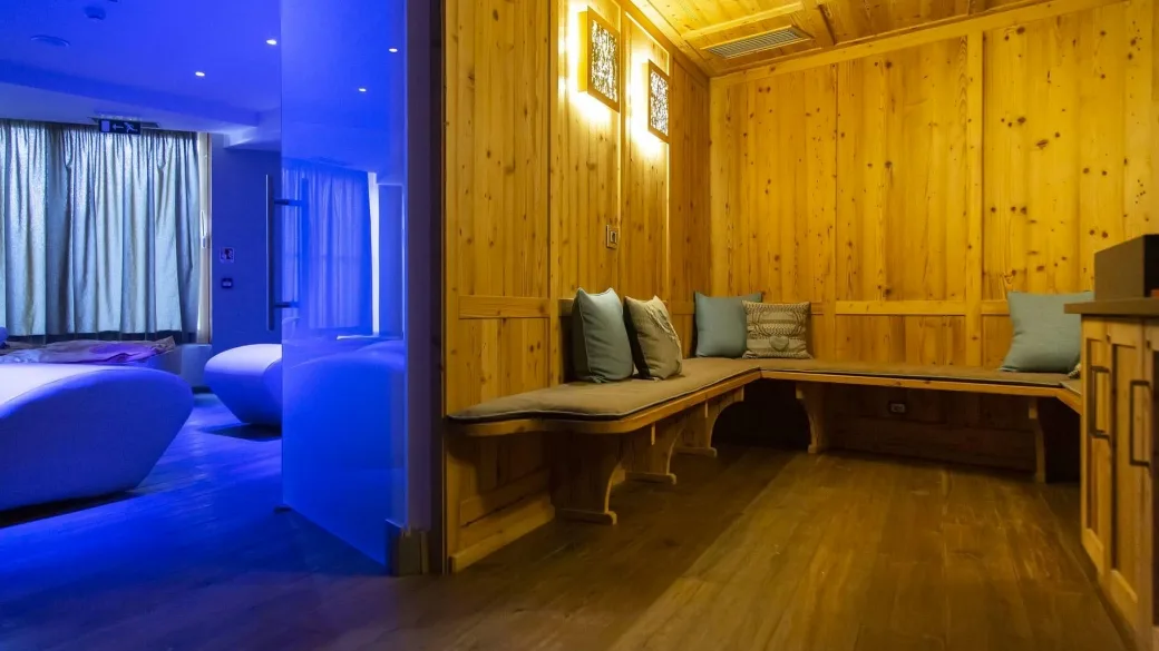 Area relax della spa con pareti in legno, panche imbottite e illuminazione blu