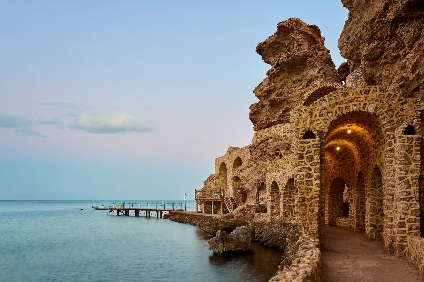 Struttura in pietra ad archi lungo la costa con pontile sul mare al crepuscolo