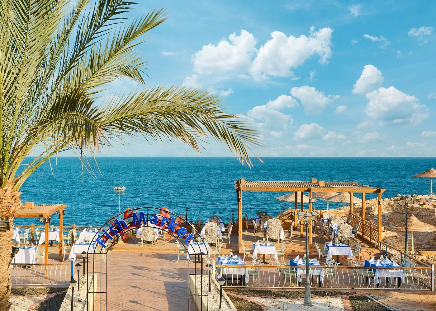 Ristorante Fish Market all'aperto con tavoli apparecchiati e pergole affacciate sul mare