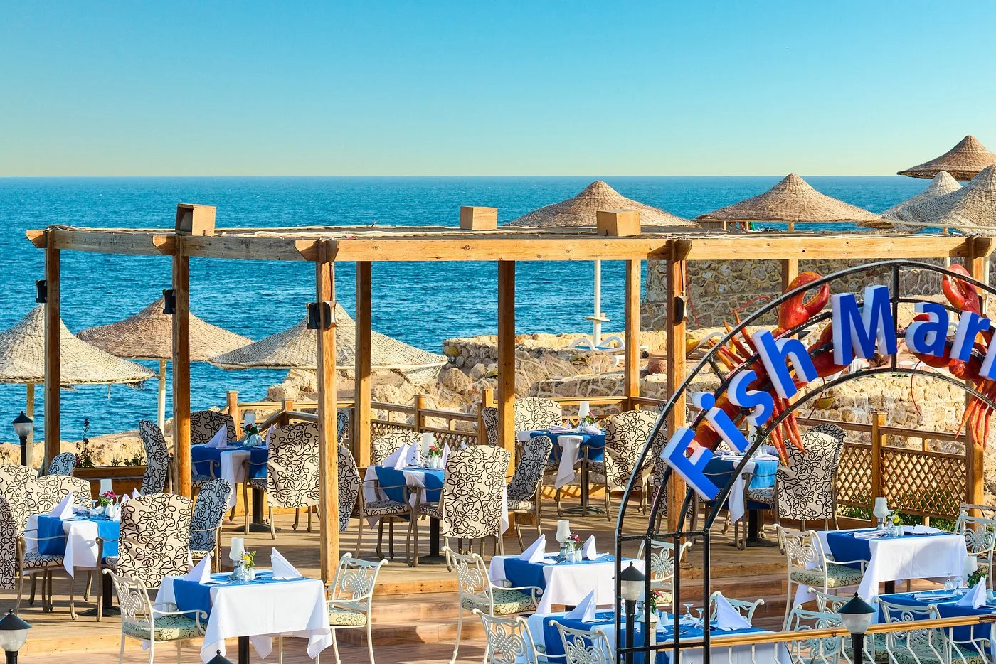 Terrazza del ristorante Fish Market con tavoli eleganti e ombrelloni di paglia vista mare