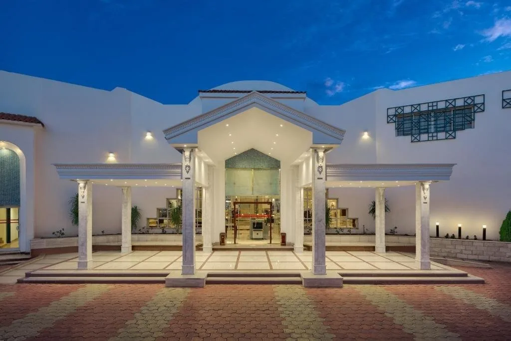 Ingresso dell'hotel illuminato al tramonto con colonne bianche e architettura elegante