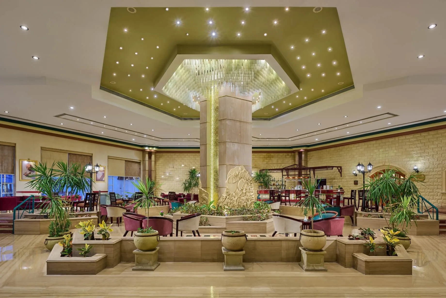 Ampia hall dell'hotel con fontana centrale, piante tropicali e soffitto decorato con luci