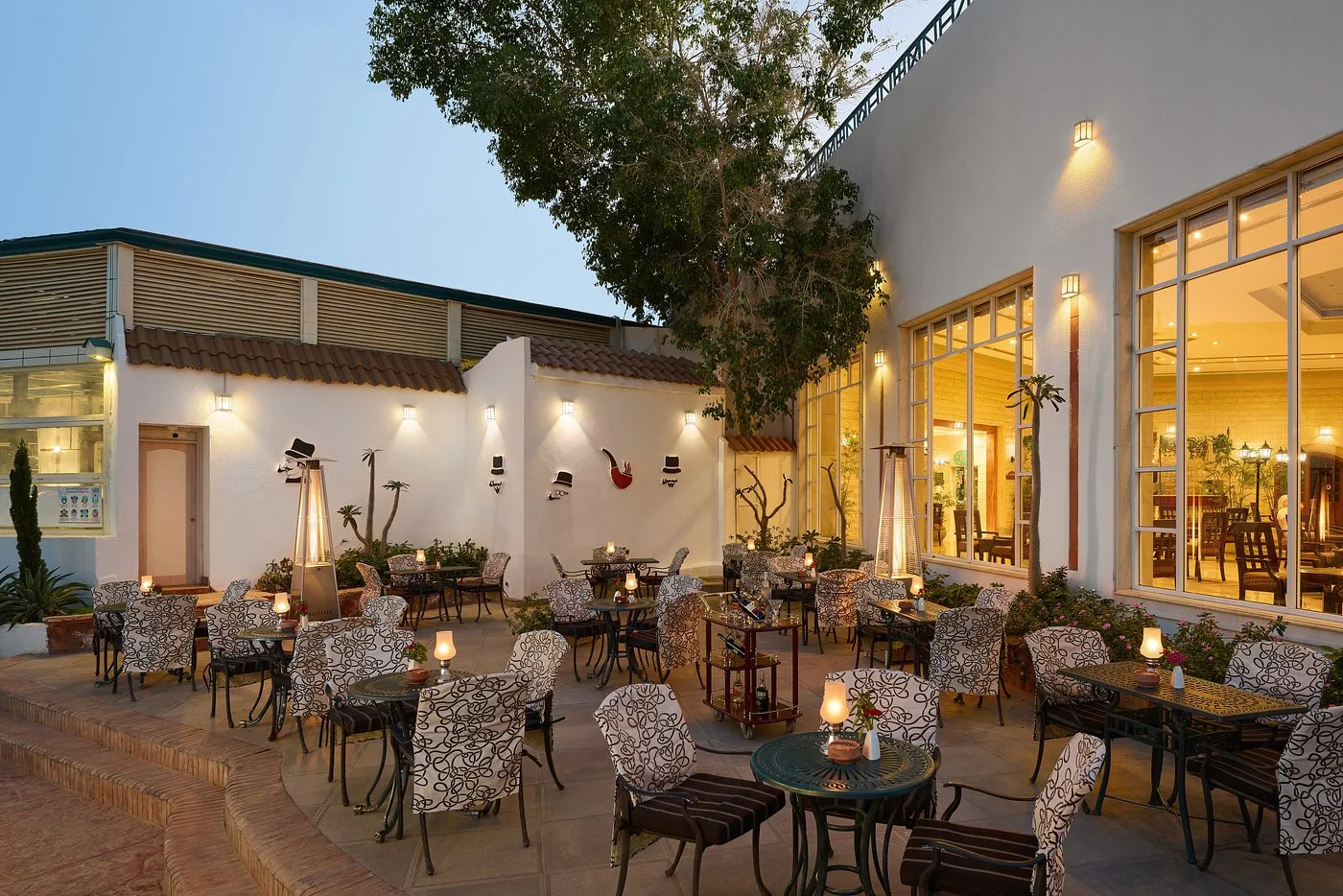 Terrazza esterna di un ristorante con tavoli in ferro battuto e illuminazione soffusa al crepuscolo