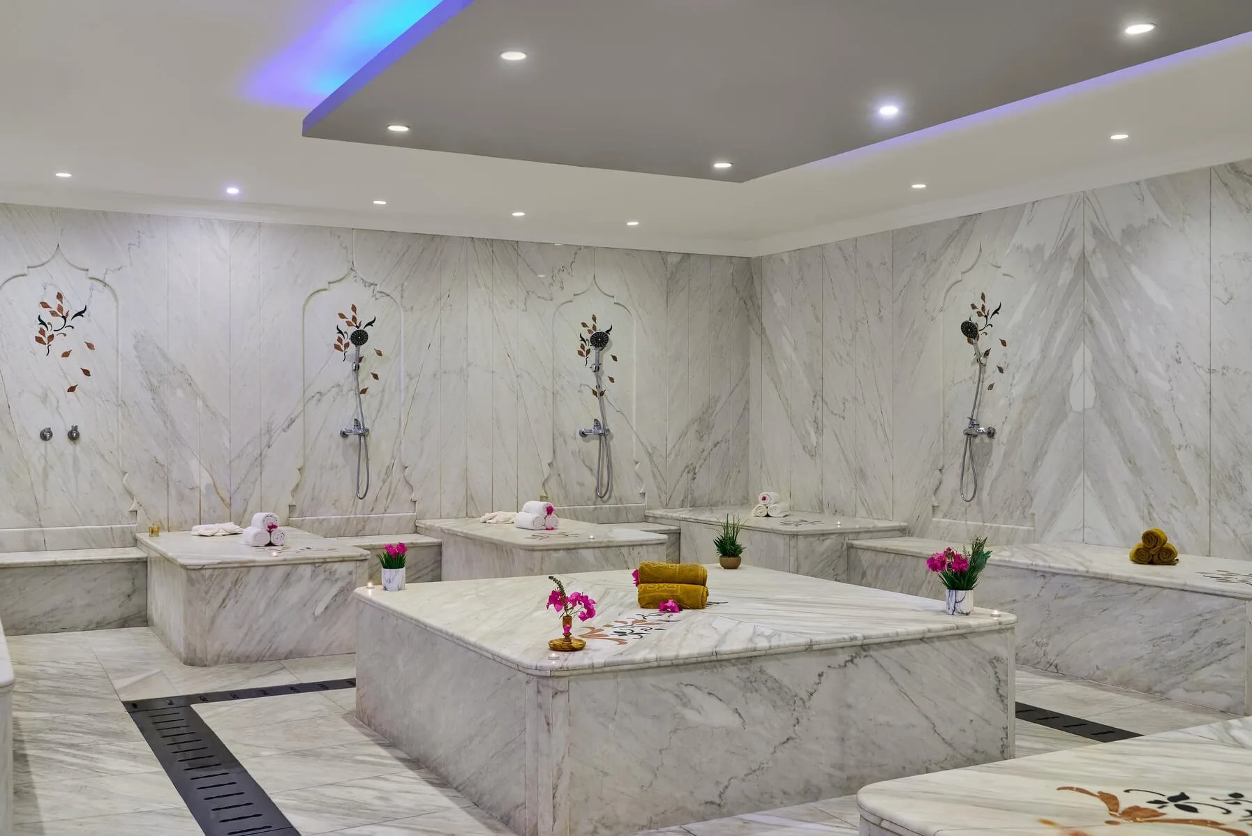 Hammam in marmo bianco con lavabi, docce e asciugamani decorativi