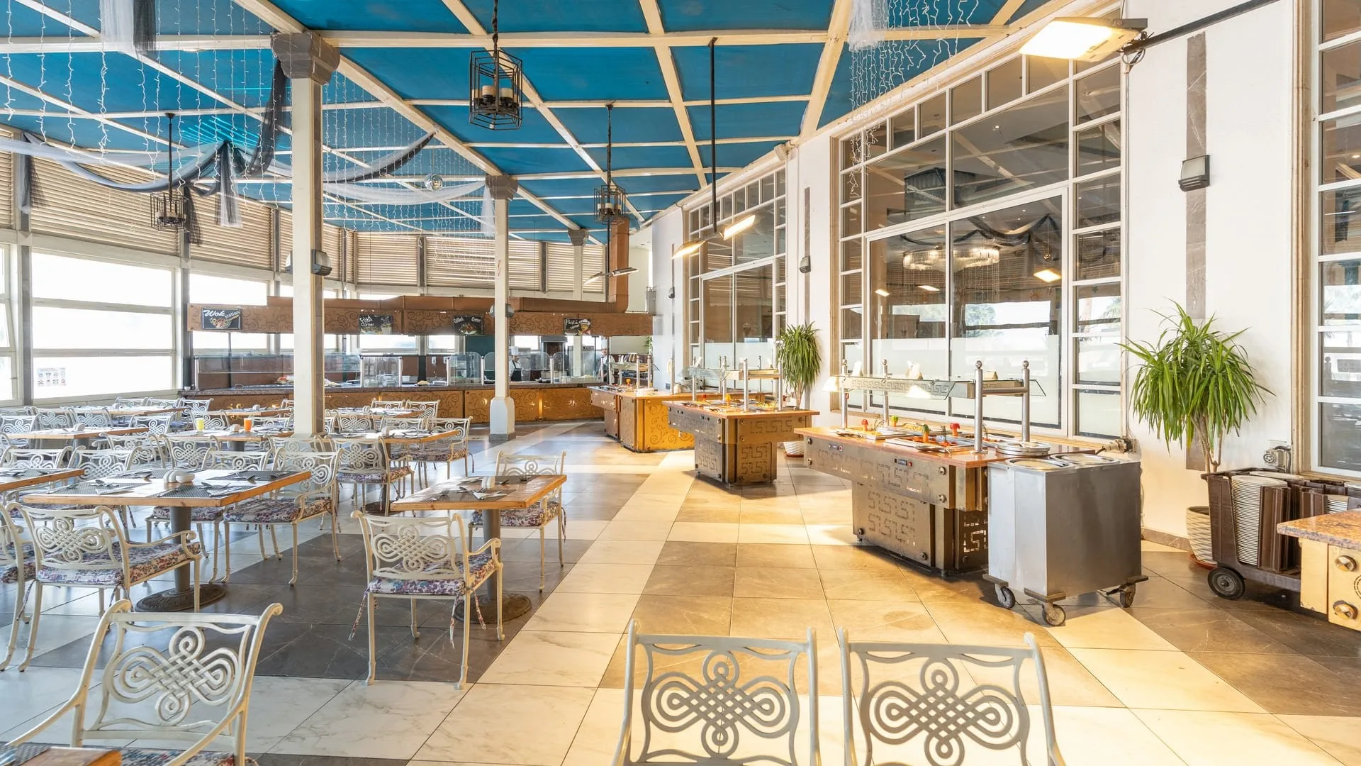 Sala ristorante a buffet luminosa con soffitto azzurro e grandi vetrate