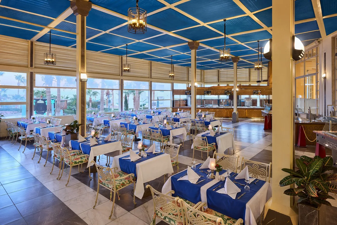 Ristorante elegante con tovaglie blu, sedie decorate e vista sui giardini