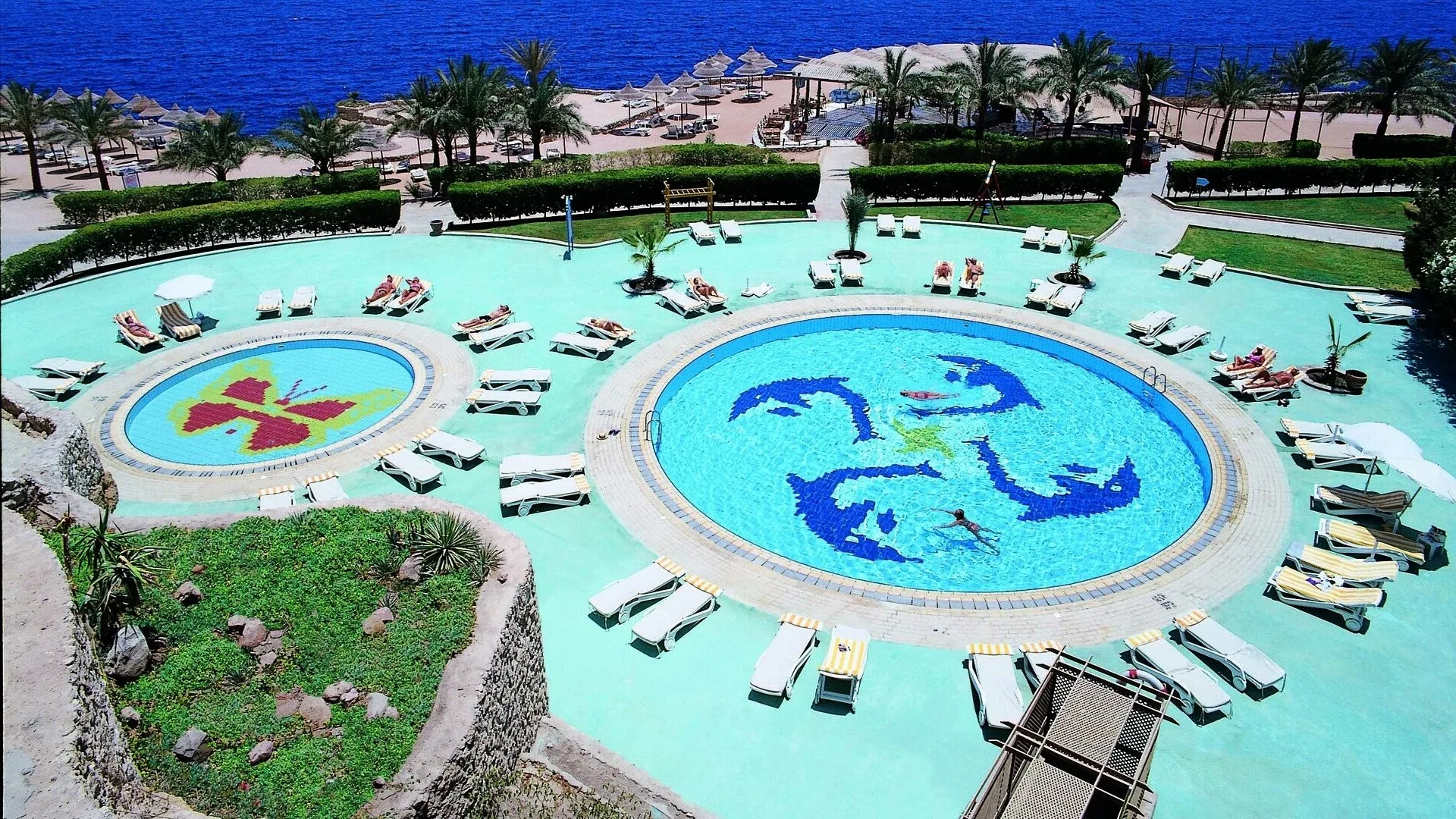 Piscine rotonde con mosaici decorativi e lettini affacciate sul mare
