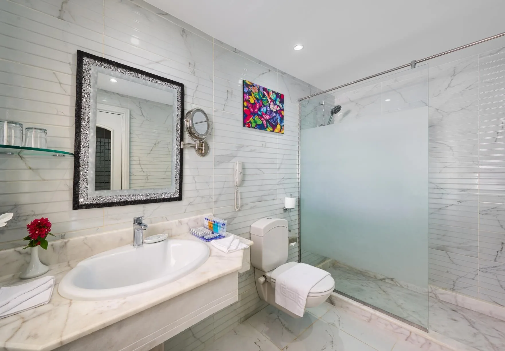 Bagno moderno in marmo con lavabo, doccia in vetro e specchio decorativo