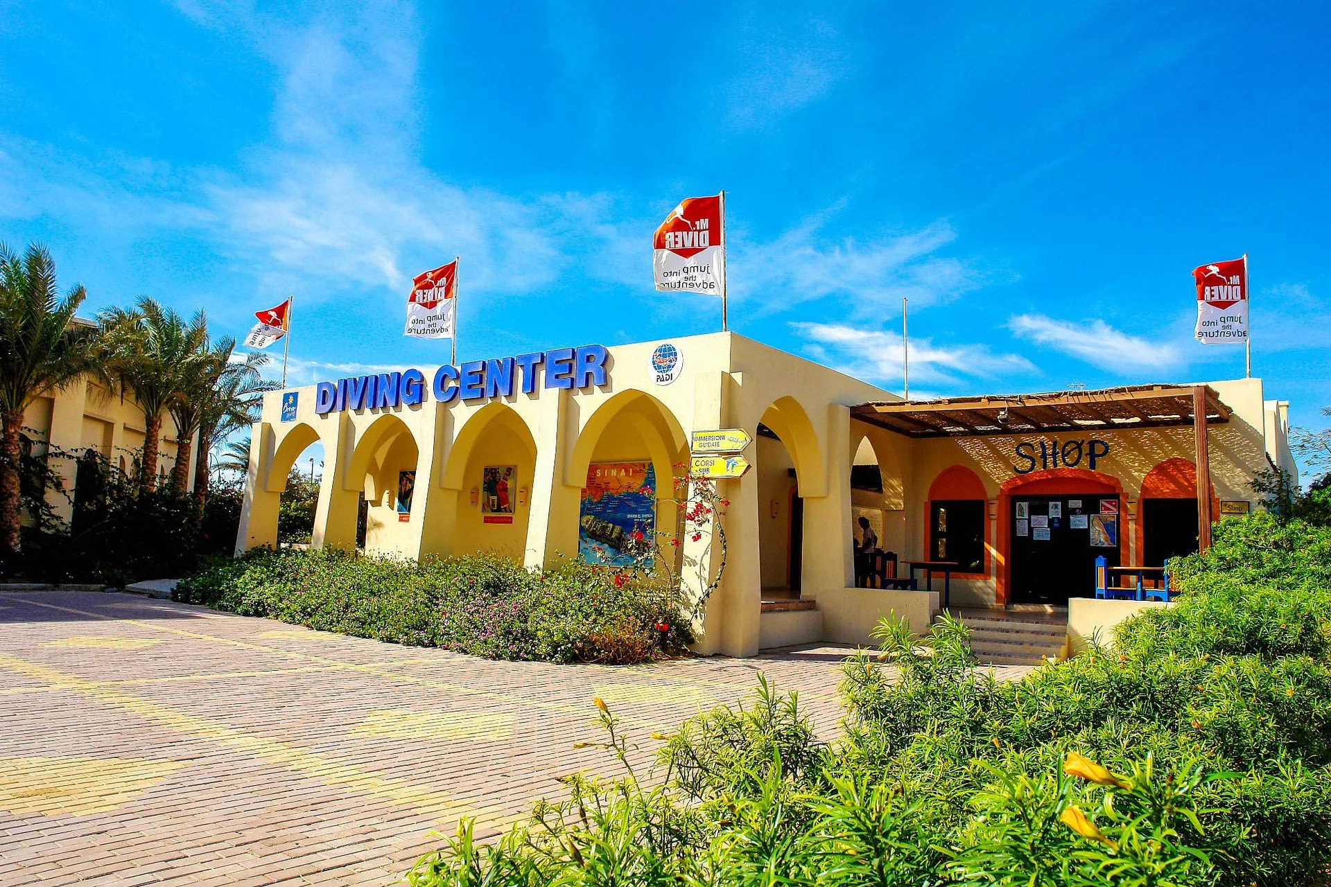 Centro diving del resort con bandiere rosse, archi e vegetazione fiorita