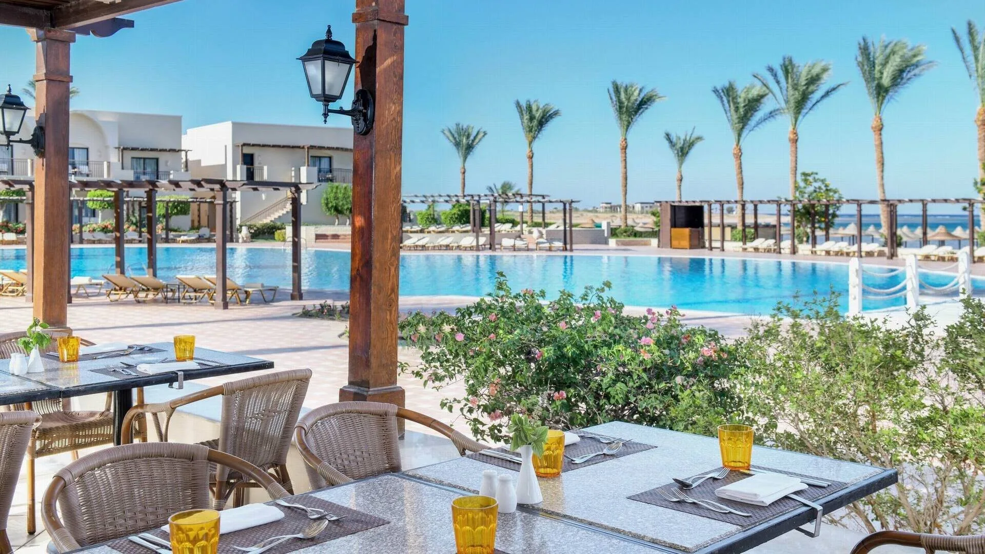 Ristorante all'aperto con tavoli apparecchiati e vista sulla piscina e sul mare