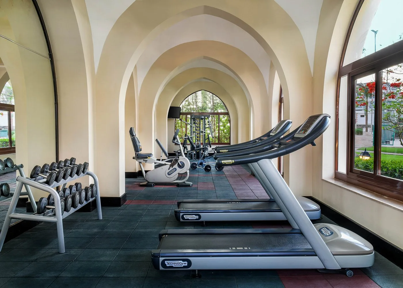 Palestra attrezzata con tapis roulant, pesi e macchinari sotto arcate ad arco