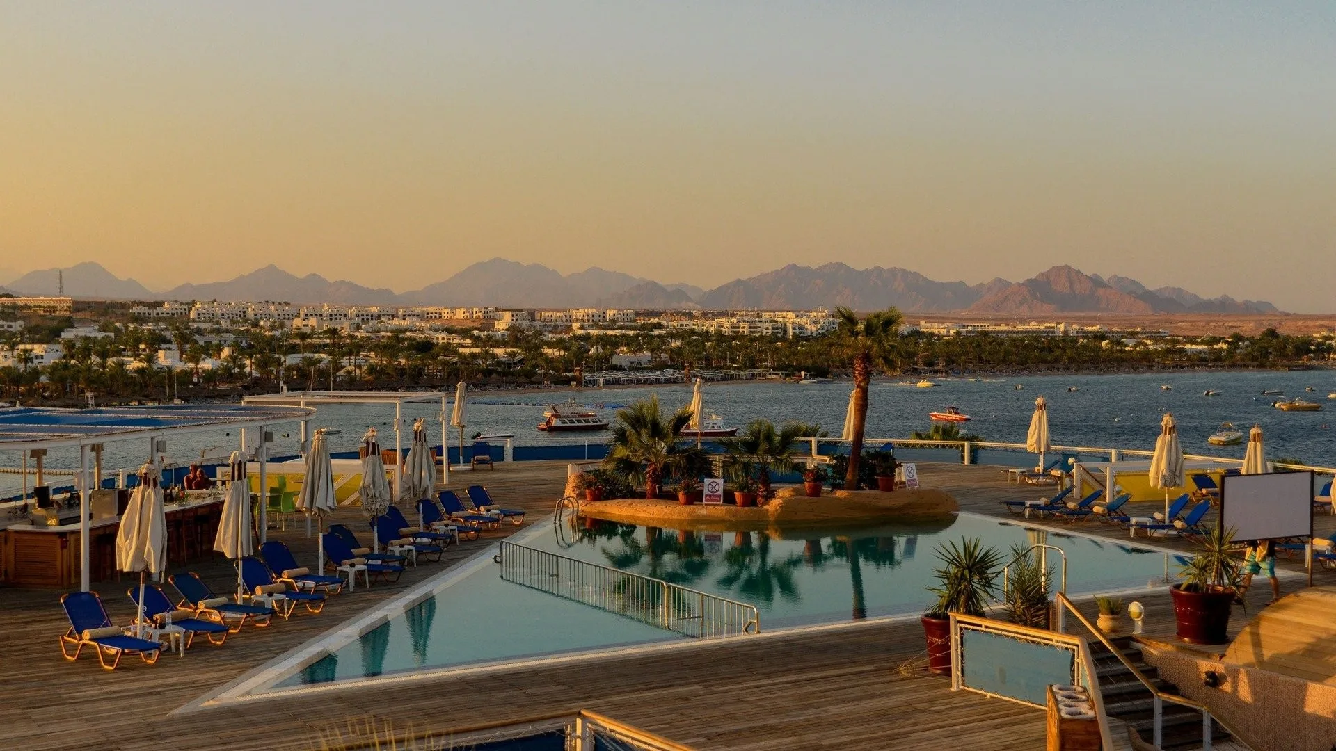 Terrazza panoramica con piscina al tramonto e vista sulla baia e le montagne di Sharm