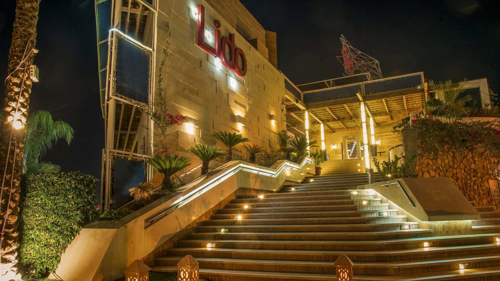 Ingresso notturno dell'hotel Lido con scalinata illuminata e palme