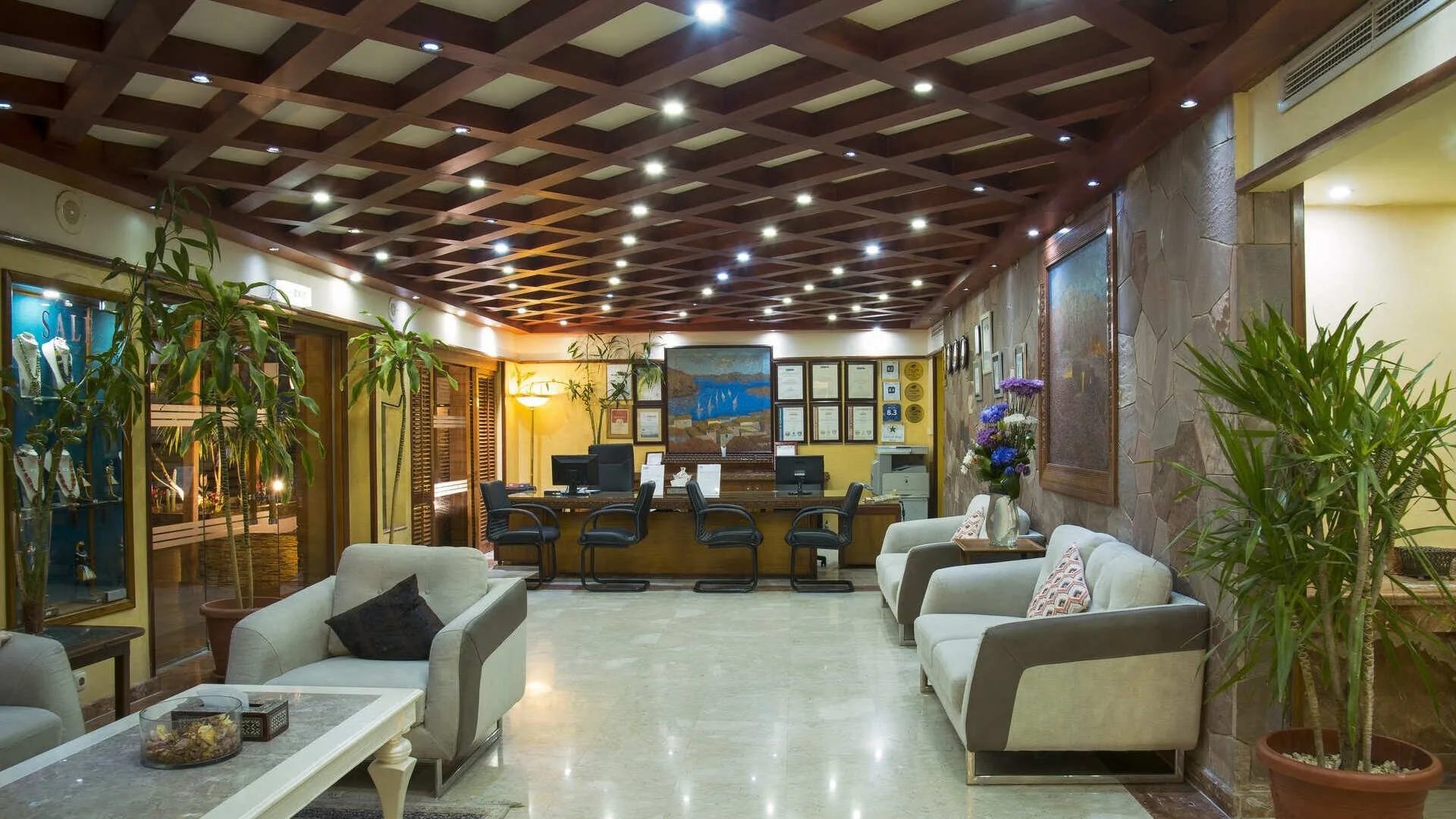 Hall dell'hotel con reception, divani eleganti, soffitto in legno e piante decorative