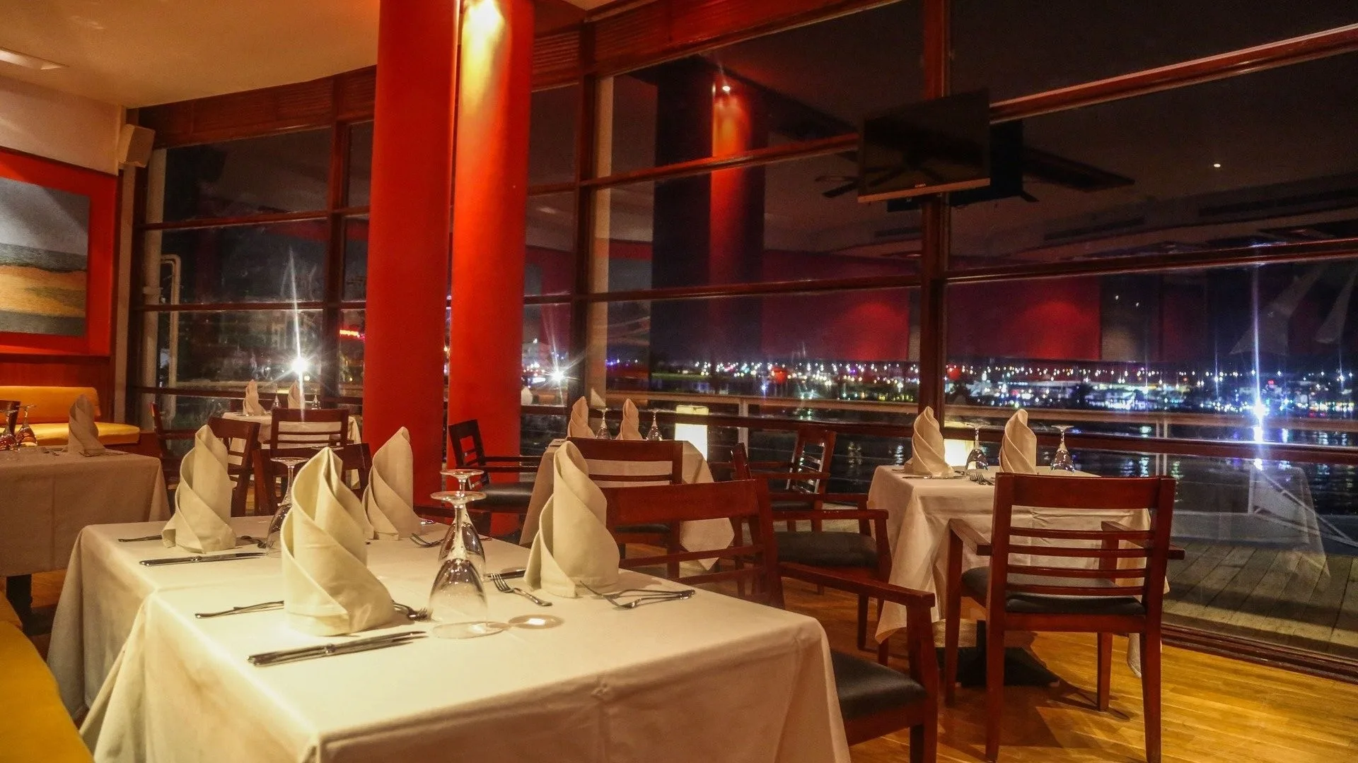 Ristorante elegante con tavoli apparecchiati e vista notturna sulle luci della città