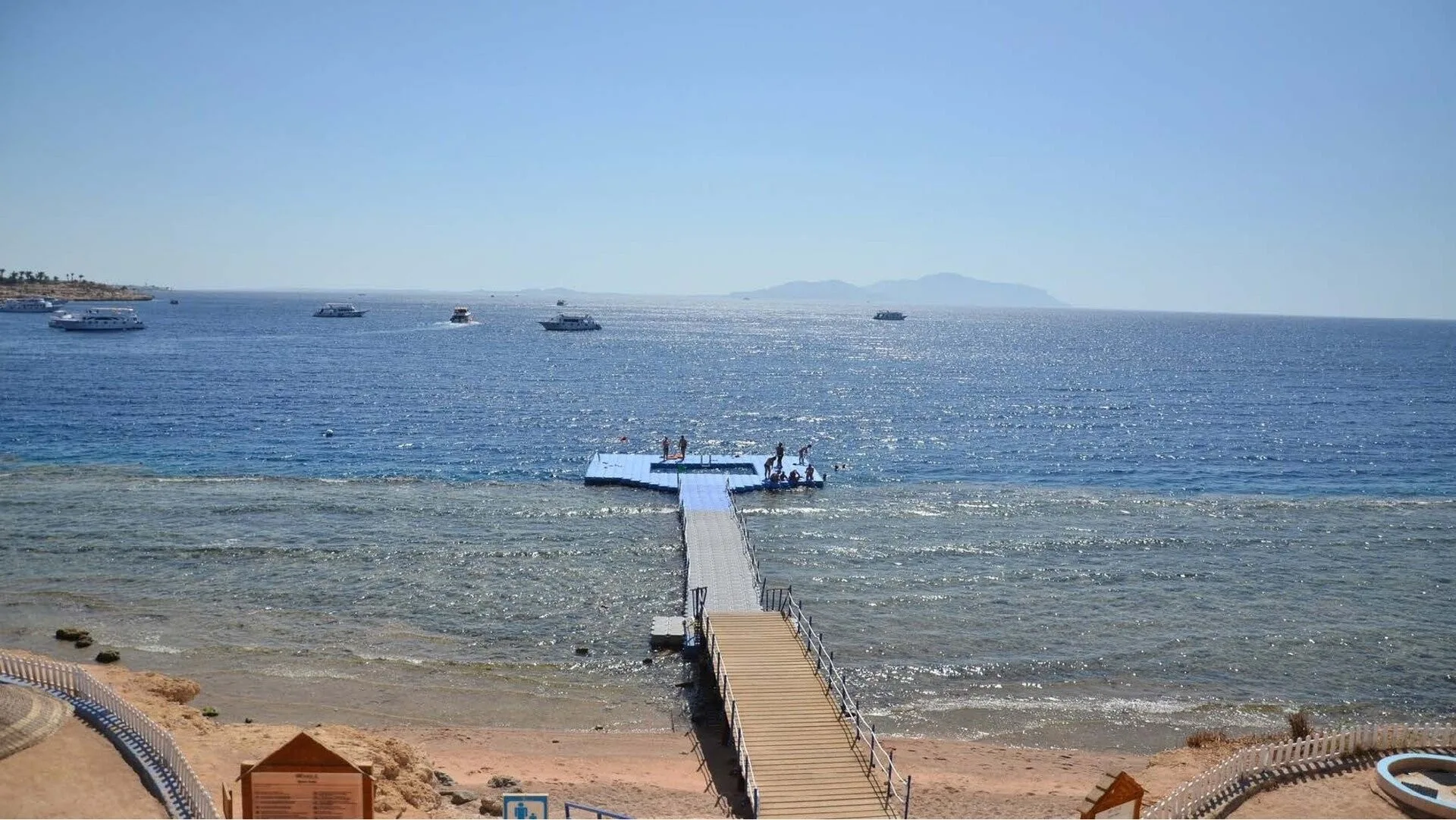 Pontile di legno che si estende sul mare con barche all'orizzonte