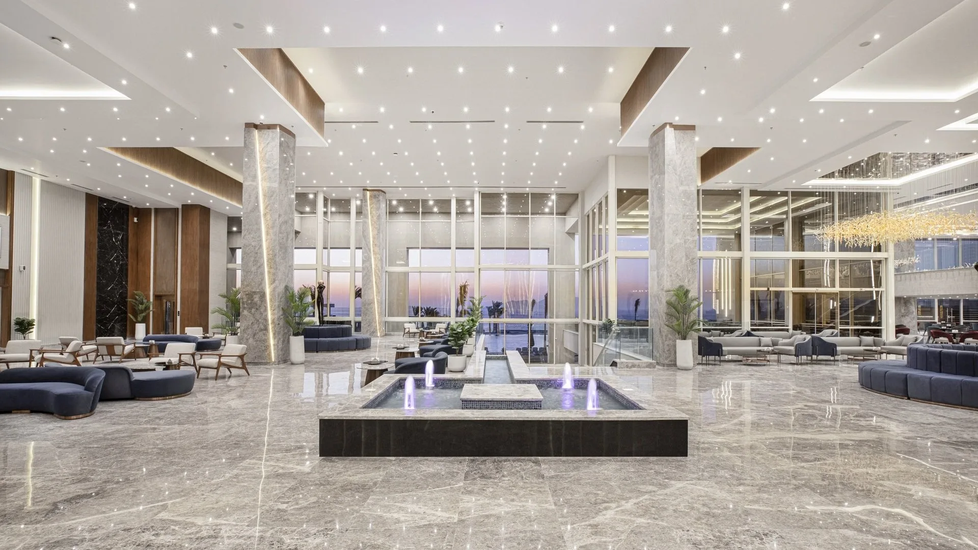 Ampia hall elegante con pavimento in marmo, fontana centrale e vetrate con vista mare