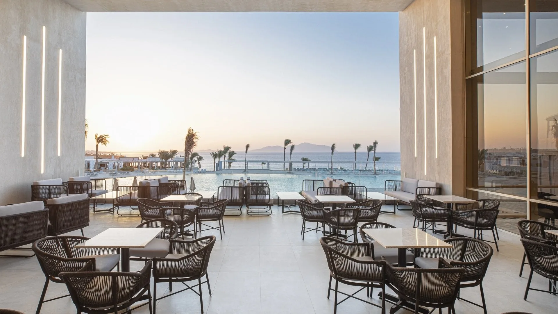 Terrazza ristorante con tavolini affacciata sulla piscina e sul mare al tramonto
