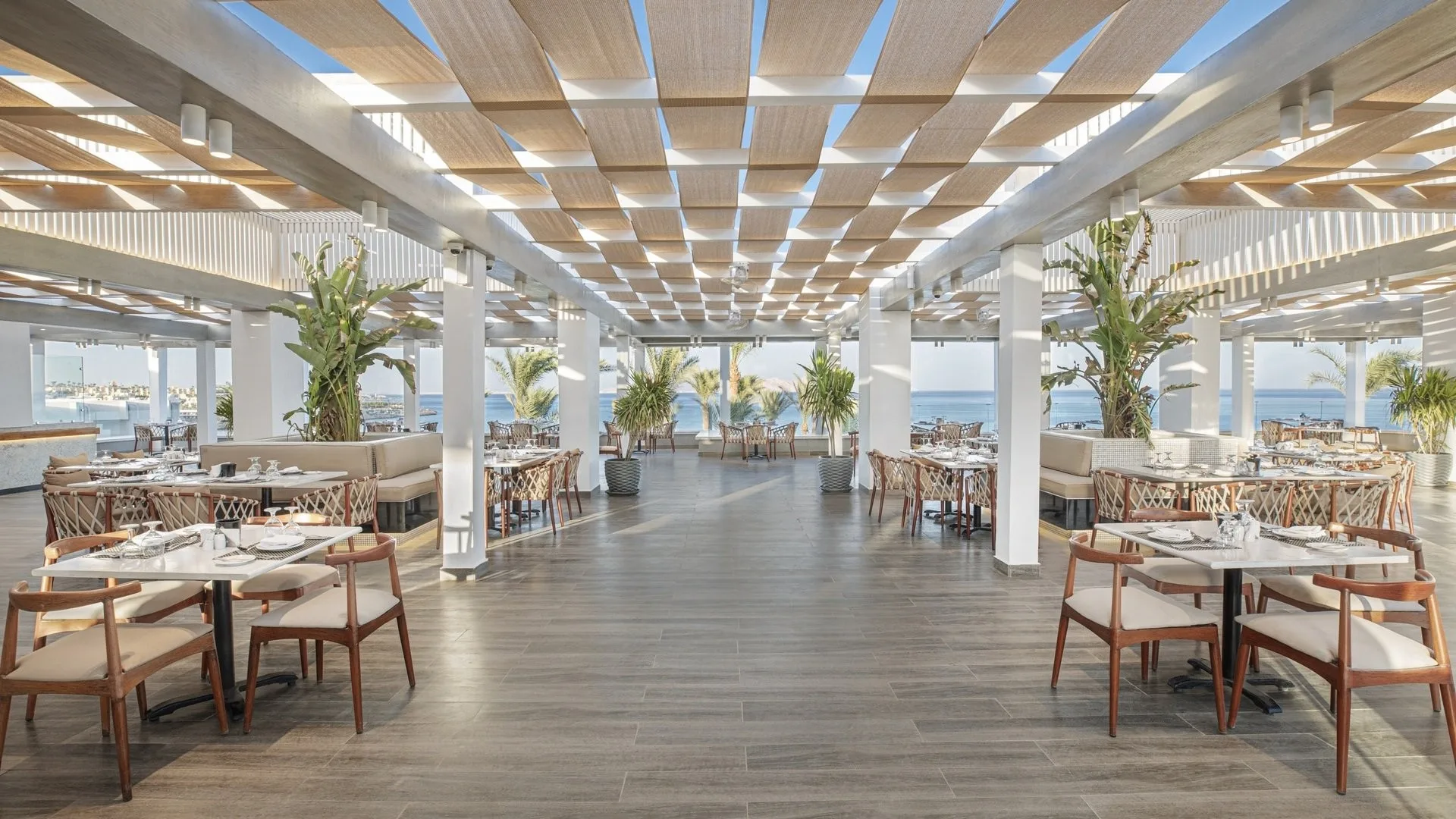 Ampia sala ristorante all'aperto con soffitto in legno, colonne bianche e vista mare