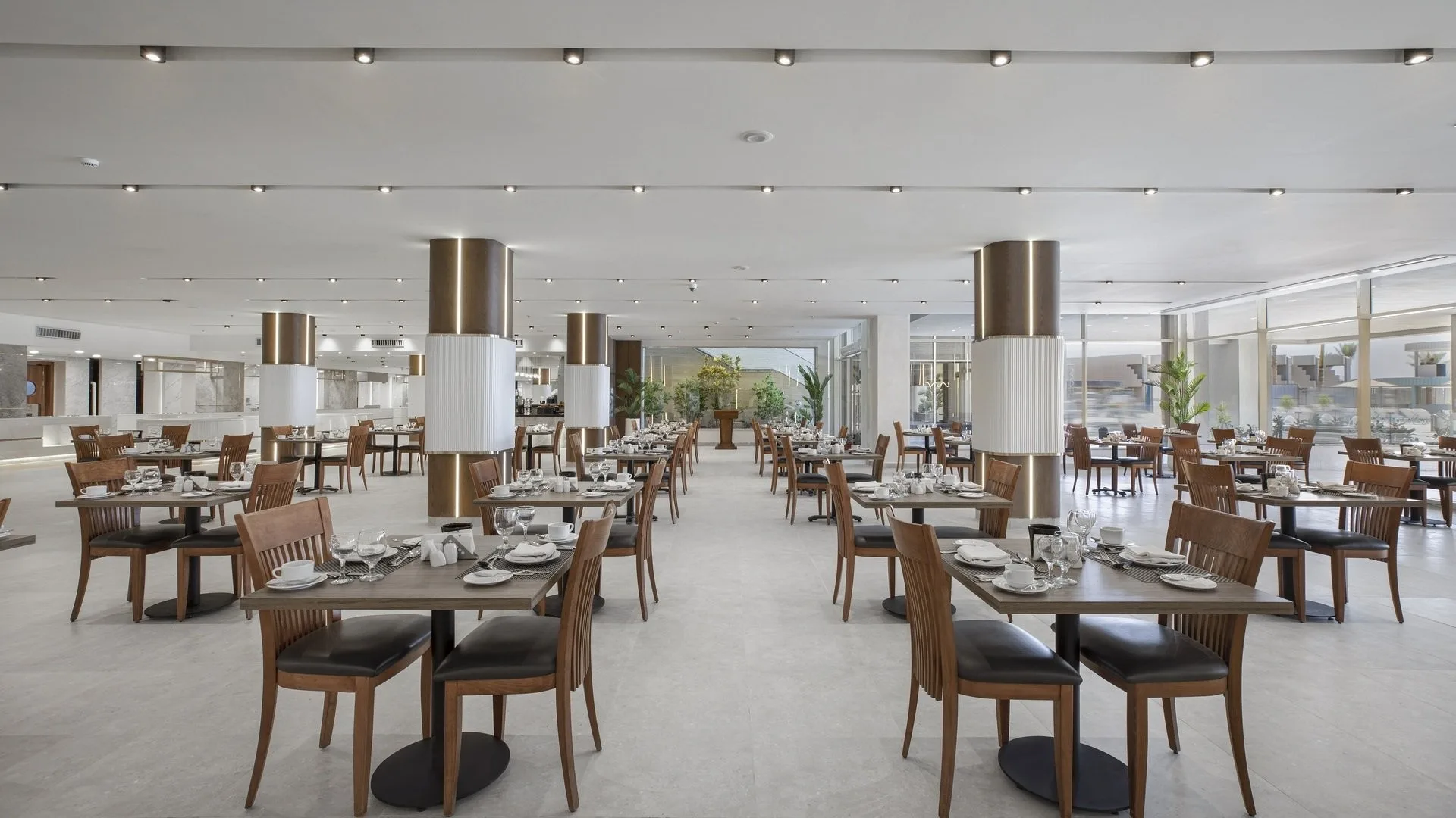 Sala ristorante interna luminosa con tavoli in legno apparecchiati e colonne decorate