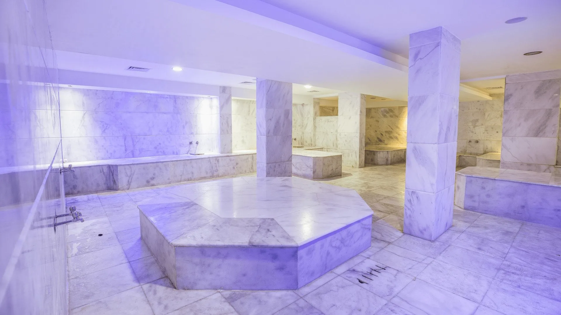 Hammam in marmo con panche e illuminazione soffusa viola