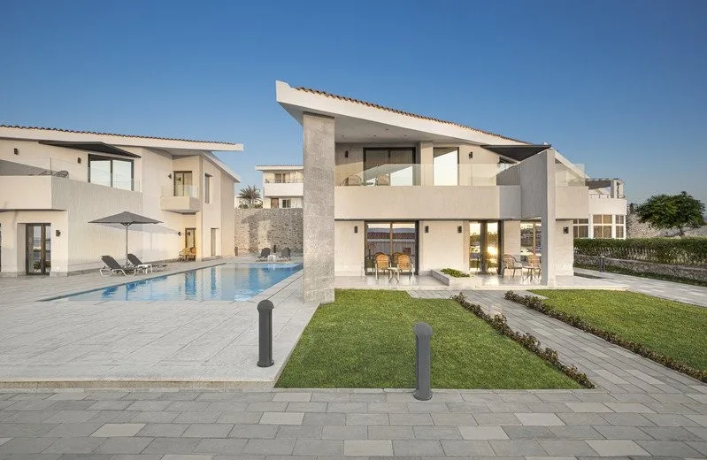 Ville moderne in pietra chiara con piscina esterna e giardino curato