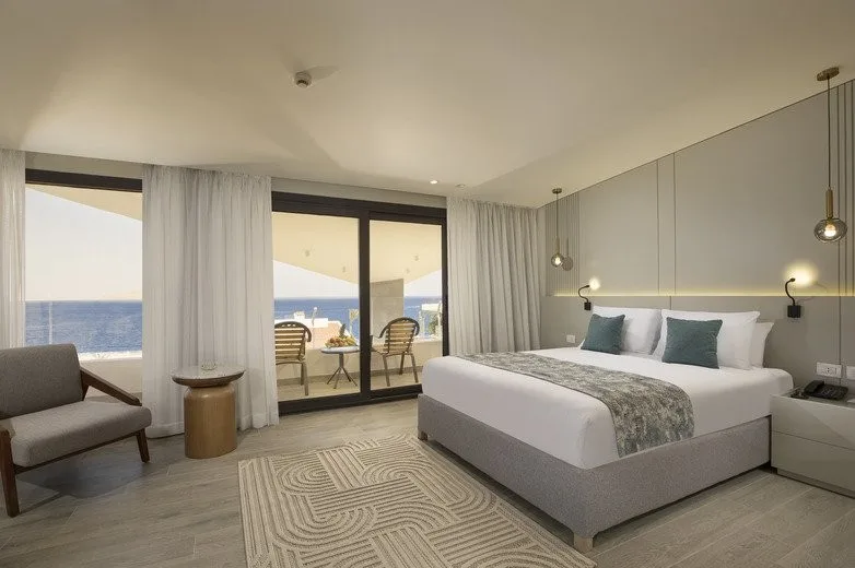 Camera elegante con letto matrimoniale, poltrona e balcone con vista mare