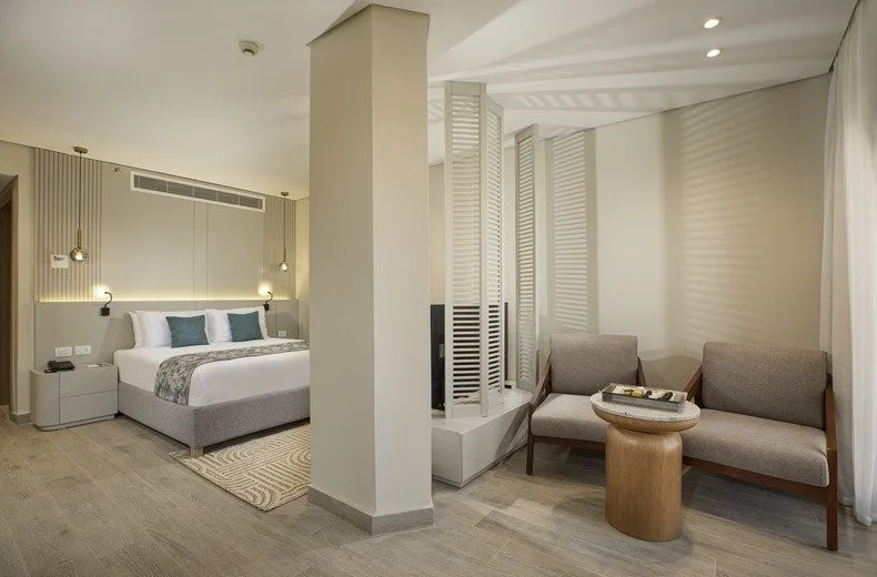 Suite moderna con letto matrimoniale, area salotto e separè in legno bianco