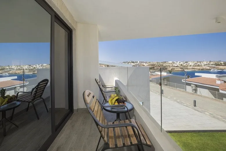Balcone con sedie in legno, frutta fresca e vista sulla città e sul porto