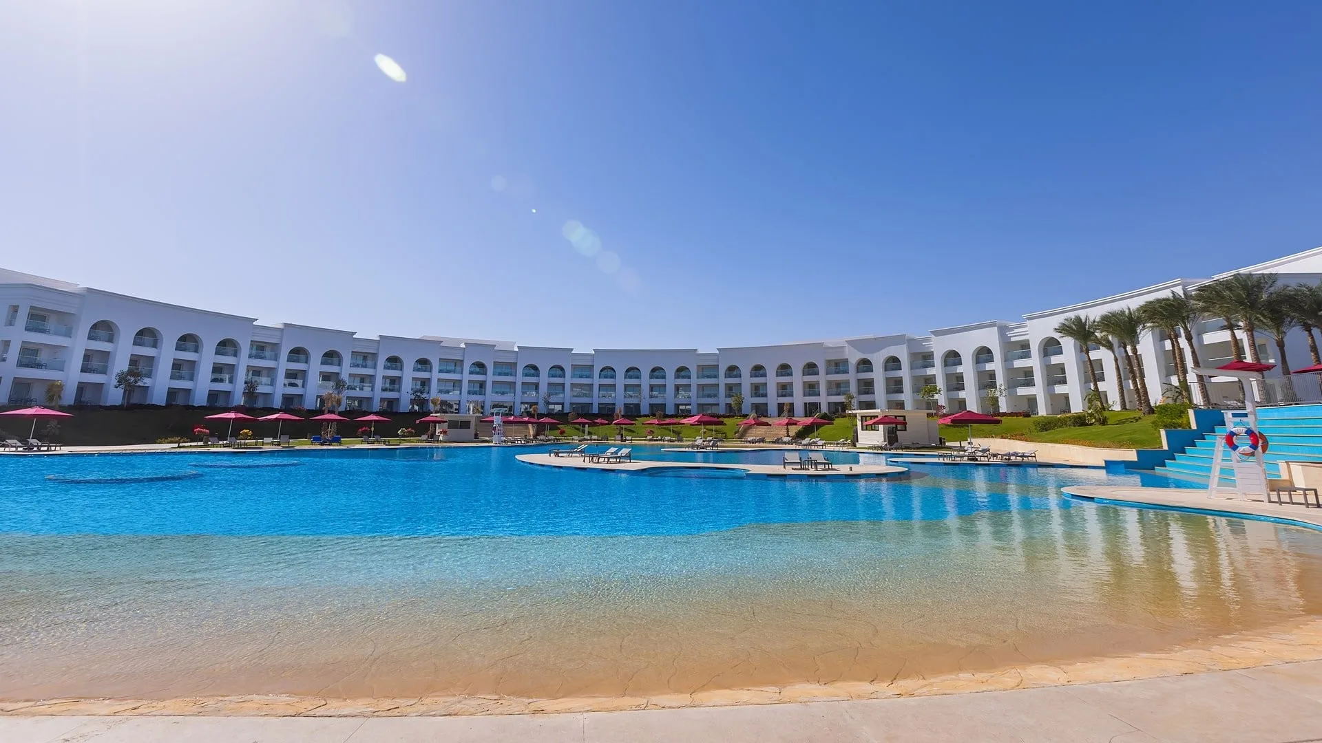 Piscina curva del resort con edificio bianco ad archi sullo sfondo