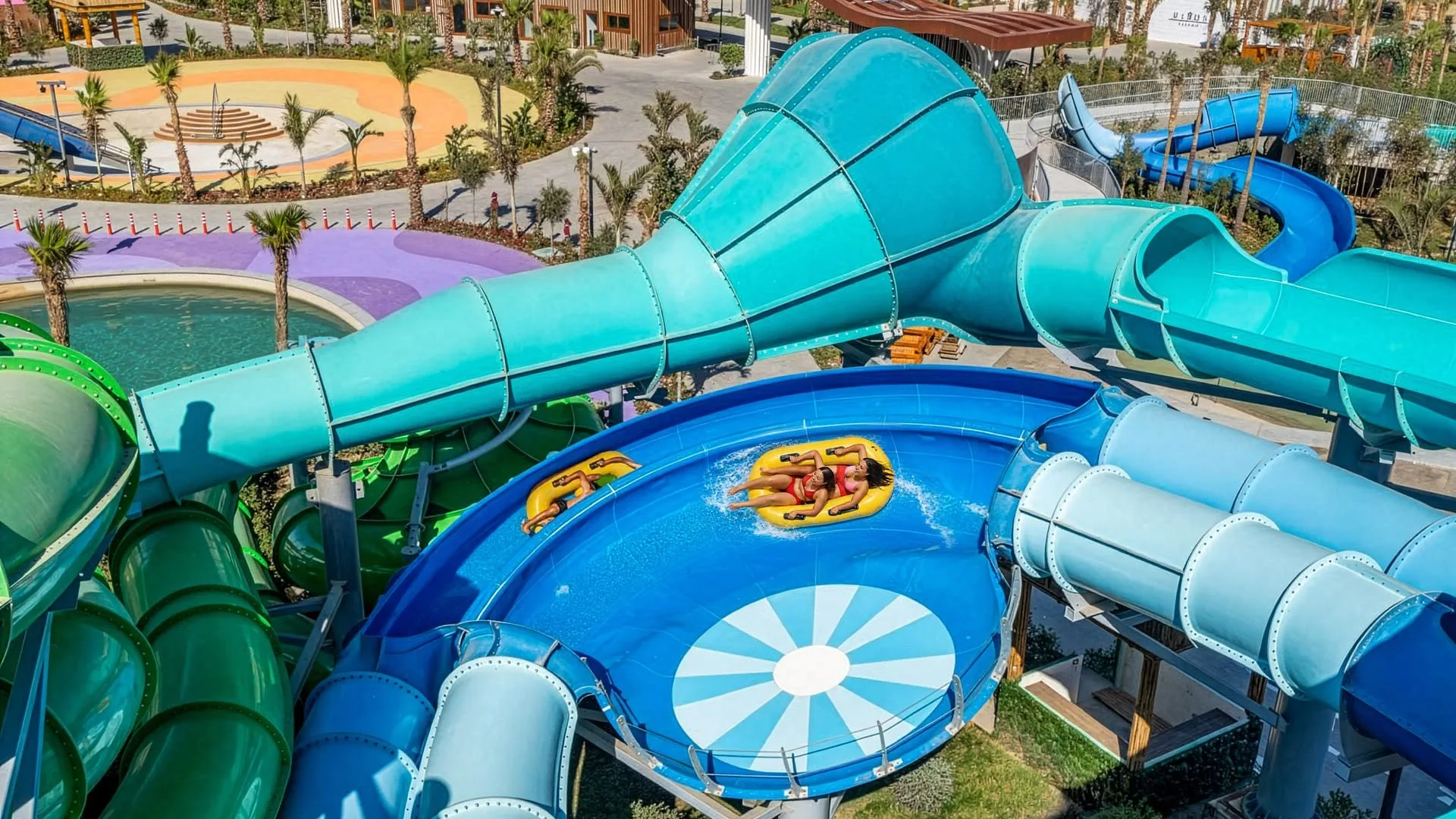 Scivoli acquatici a spirale con persone che scendono su gommoni gialli