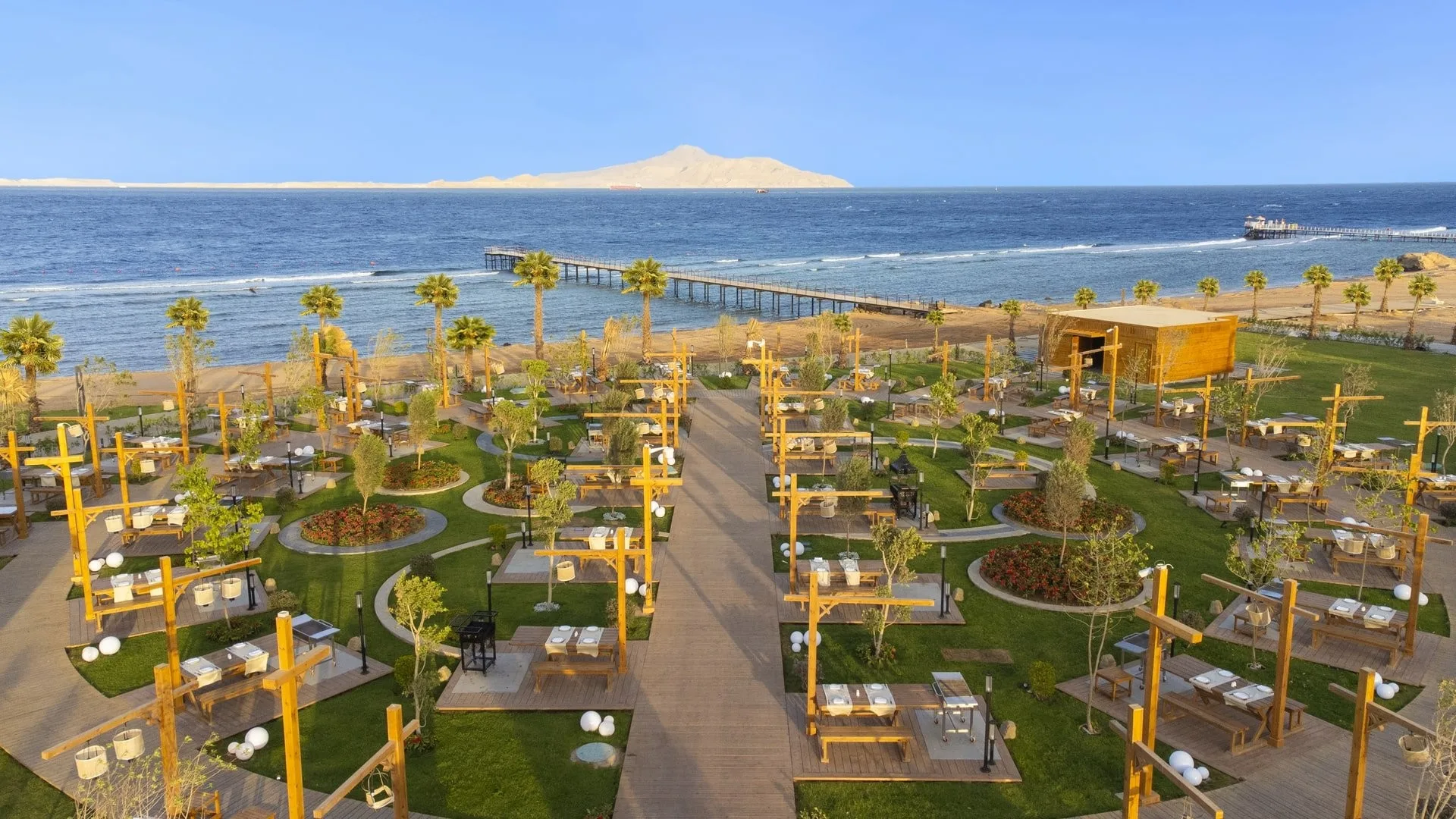 Ristorante all'aperto in giardino con tavoli e vista sul mare e pontile
