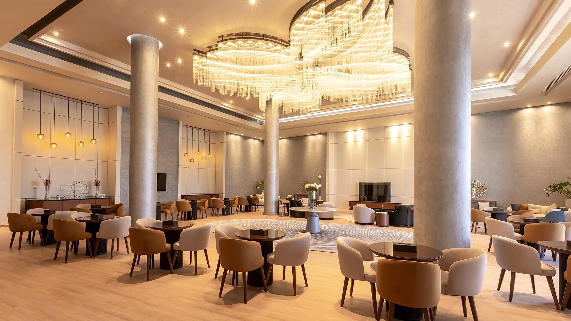 Sala lounge interna con tavoli, poltrone e grande lampadario moderno