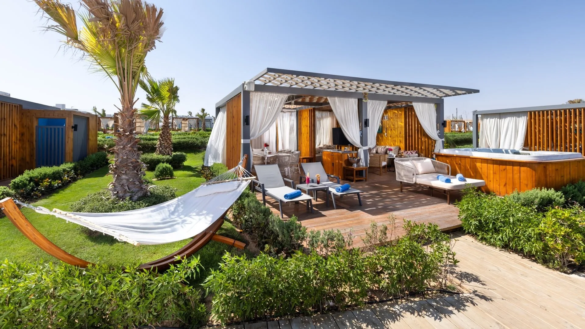 Cabana privata con pergola, amaca, lettini e vasca idromassaggio in giardino tropicale con palme