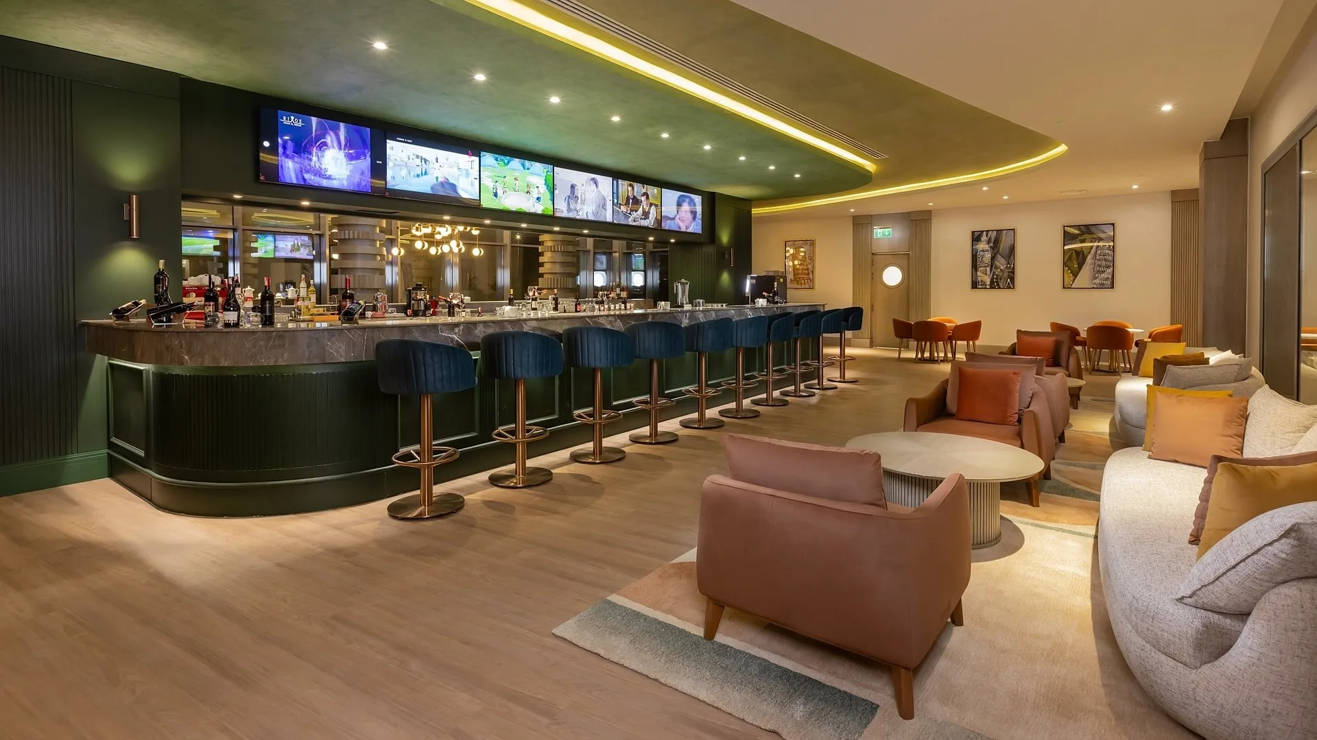 Bar lounge con bancone verde, sgabelli blu e area salotto accogliente