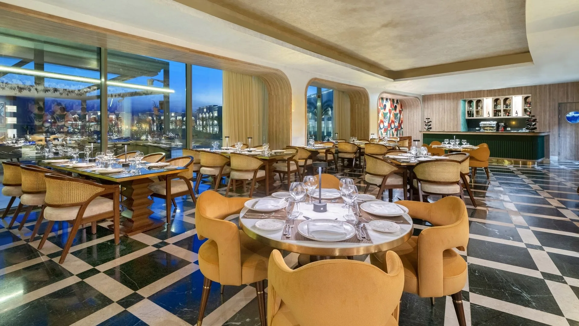 Ristorante con pavimento a scacchi, tavoli apparecchiati e vista serale sulle vetrate