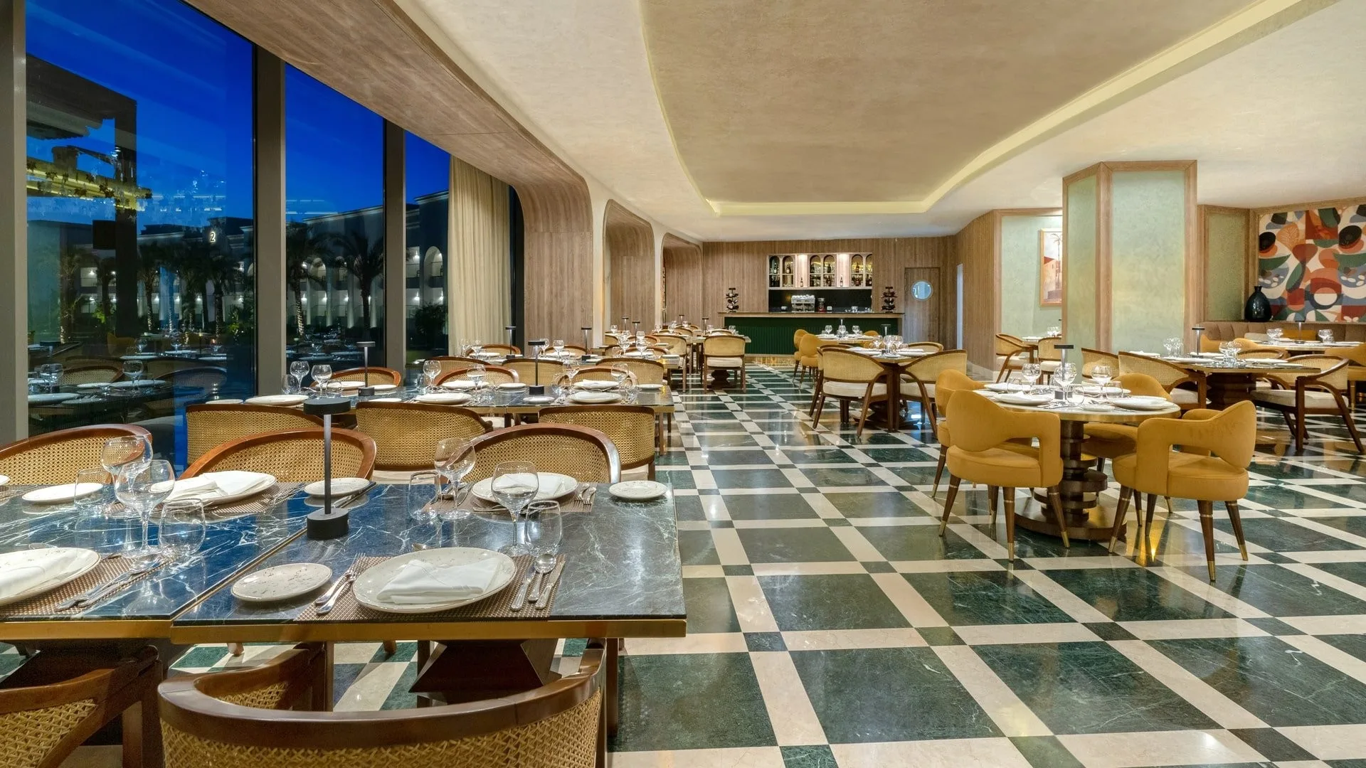 Sala ristorante raffinata con pavimento a scacchi verde e grandi vetrate al tramonto