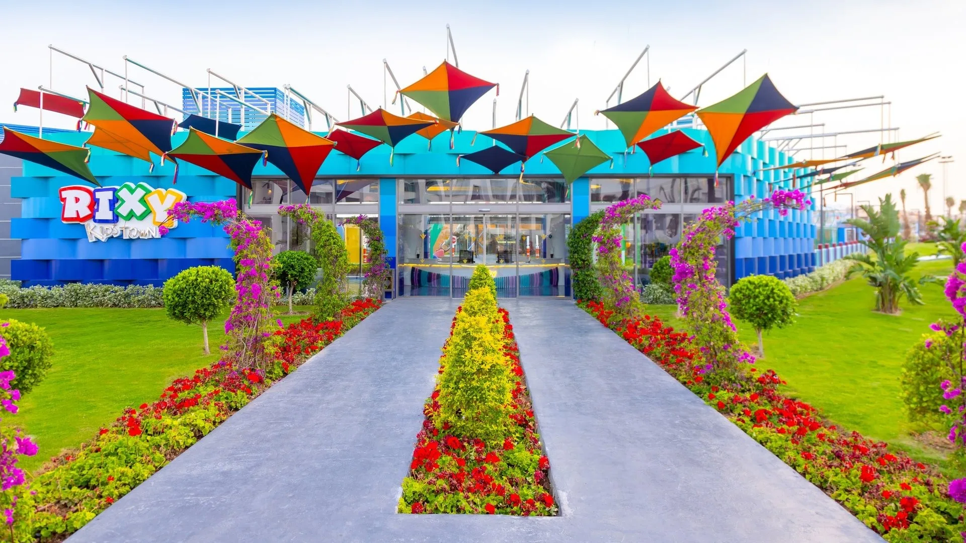 Ingresso colorato del Rixy Kids Town con vele decorative e aiuole fiorite