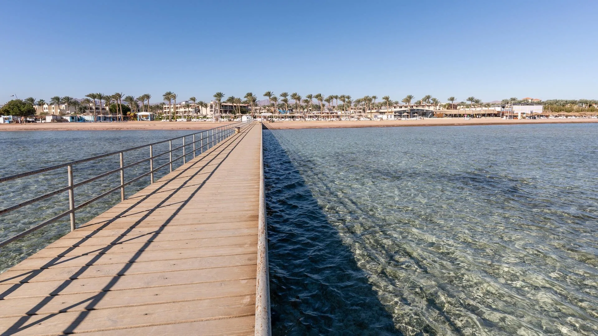 Pontile di legno che si estende sul mare cristallino verso la spiaggia del resort