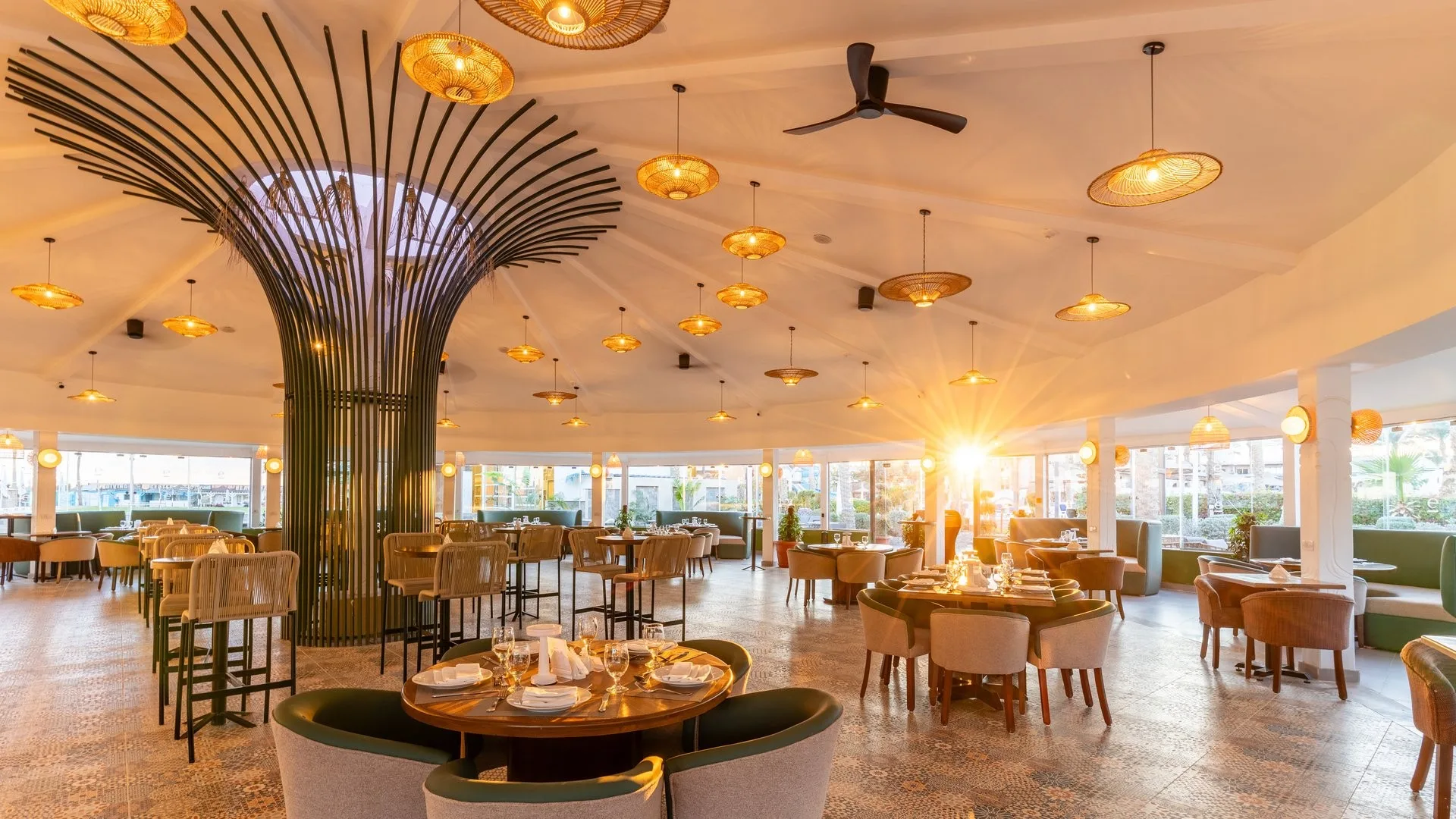 Ristorante elegante con lampadari in rattan, tavoli apparecchiati e luce del tramonto