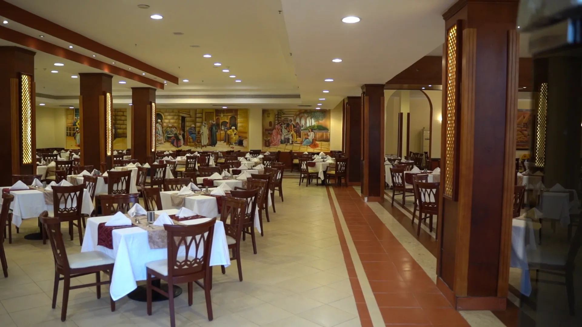 Ristorante interno con tavoli apparecchiati, colonne in legno e affreschi alle pareti