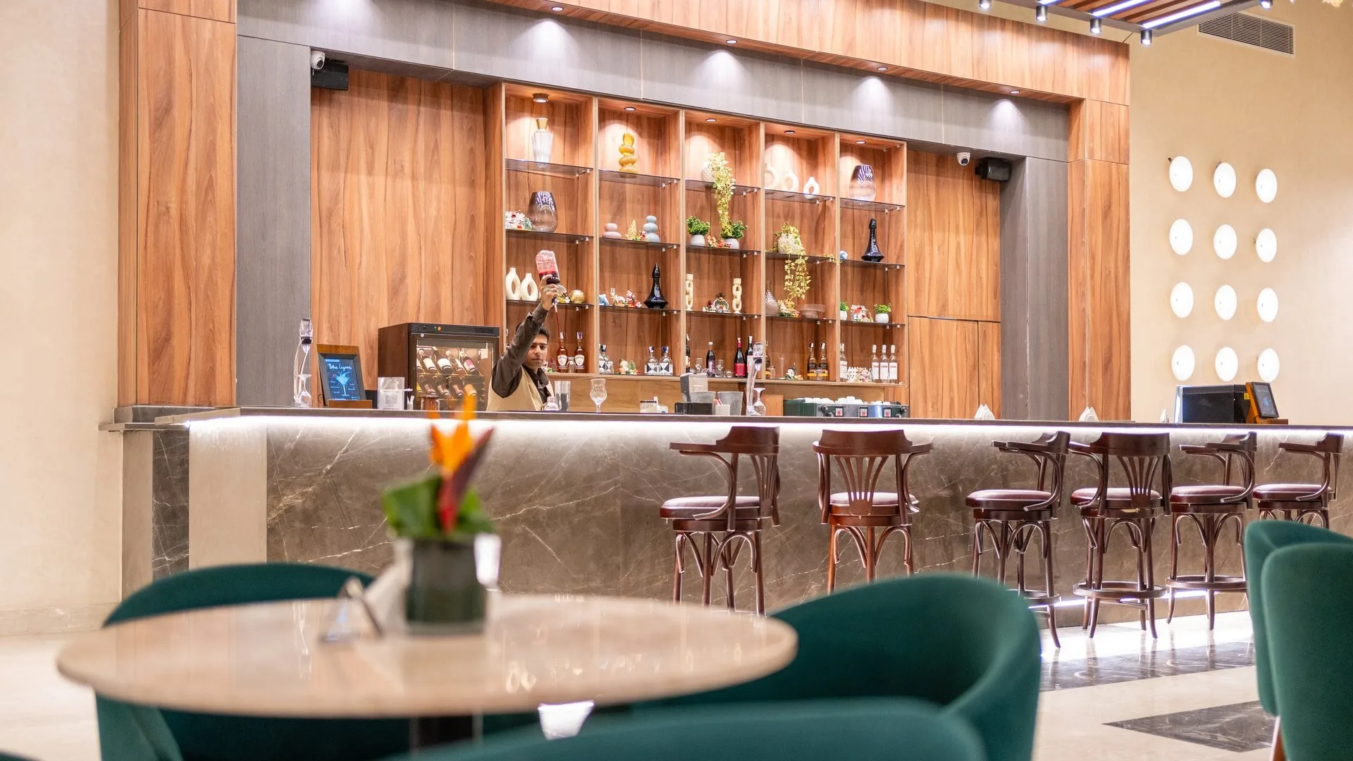 Bar del resort con bancone in marmo, scaffali in legno e sgabelli