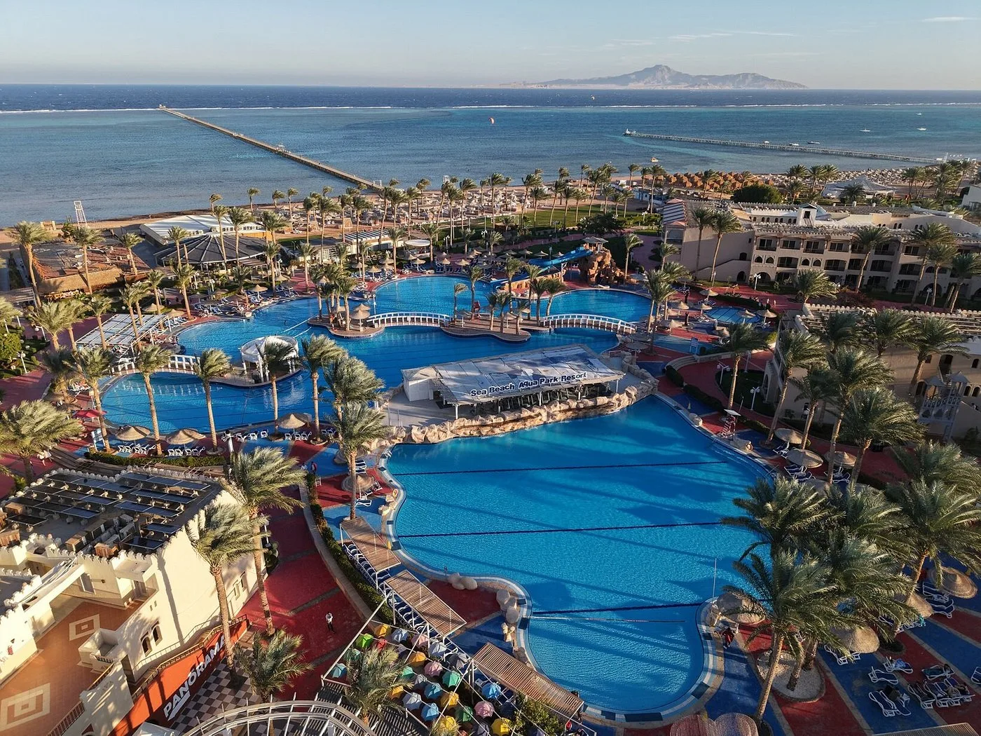 Vista aerea del grande complesso di piscine del resort con palme e mare sullo sfondo