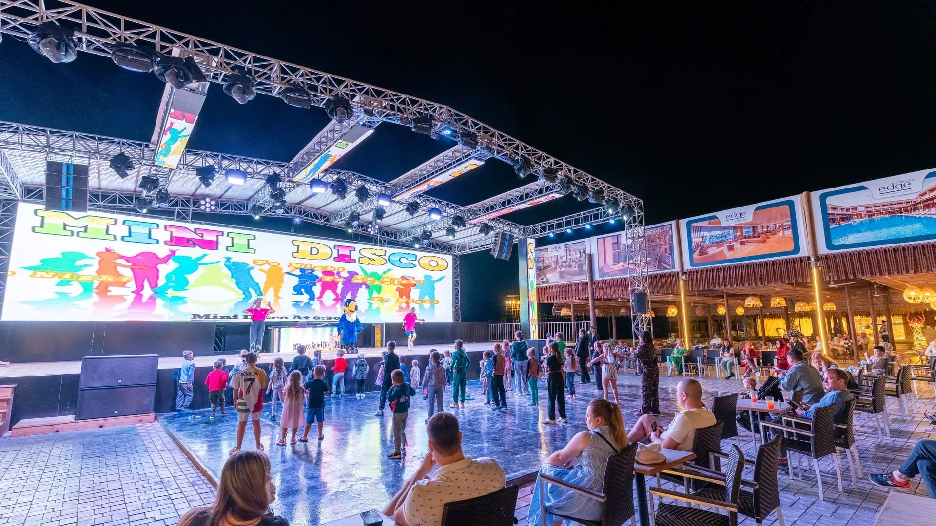 Spettacolo serale di mini disco con palco illuminato e ospiti del resort