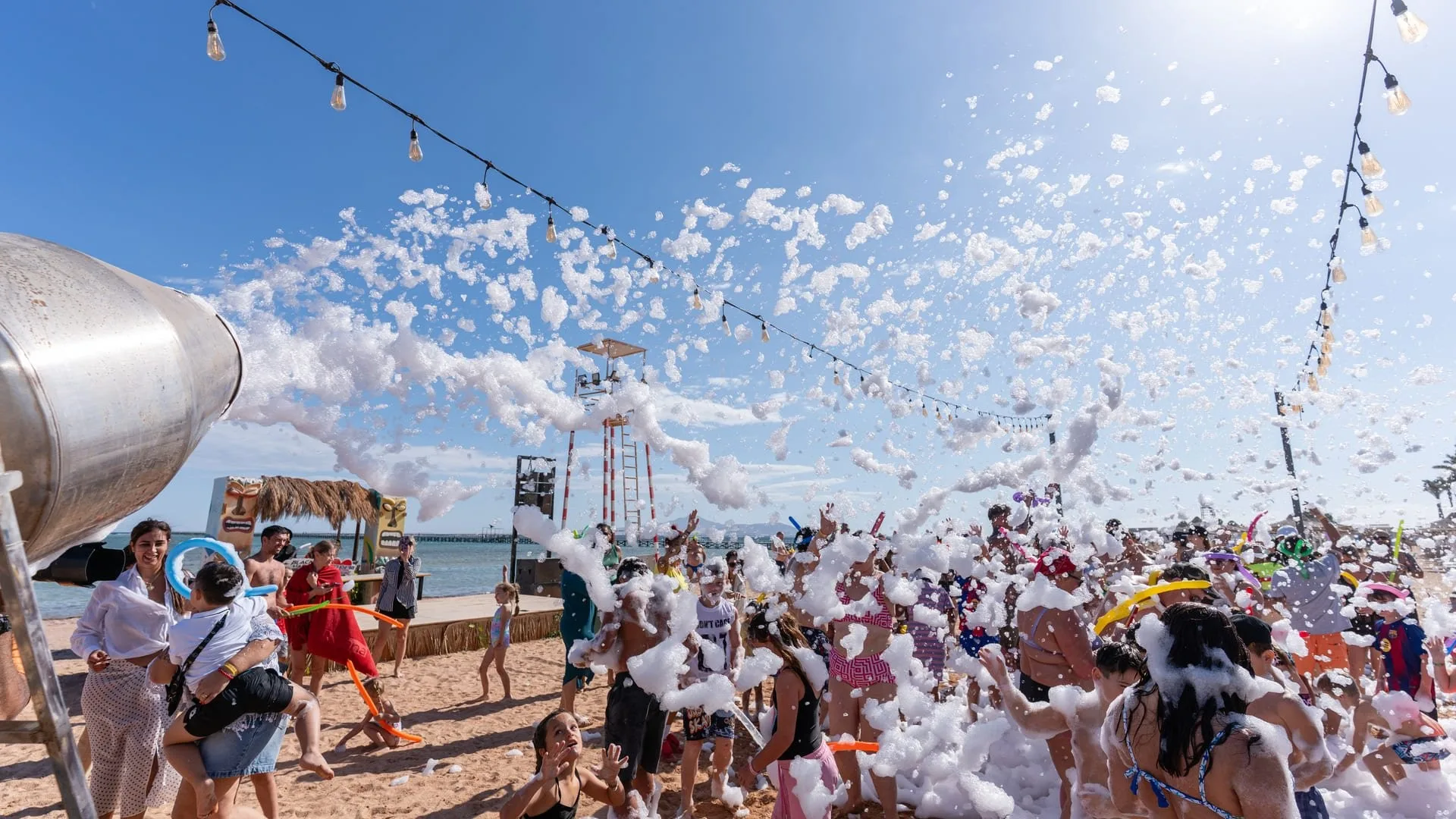 Festa della schiuma in spiaggia con bagnanti divertiti sotto il sole