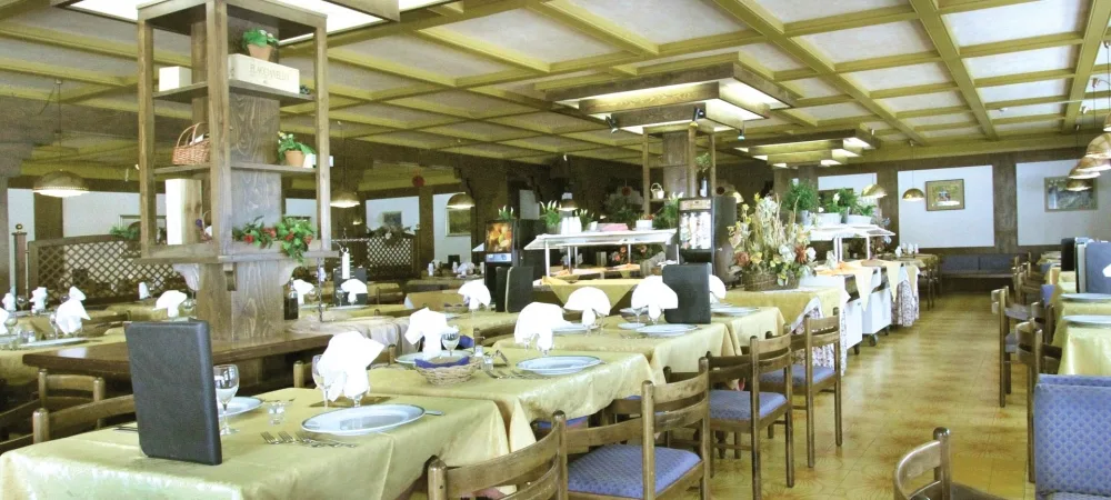 Ampia sala ristorante con tavoli apparecchiati e buffet centrale