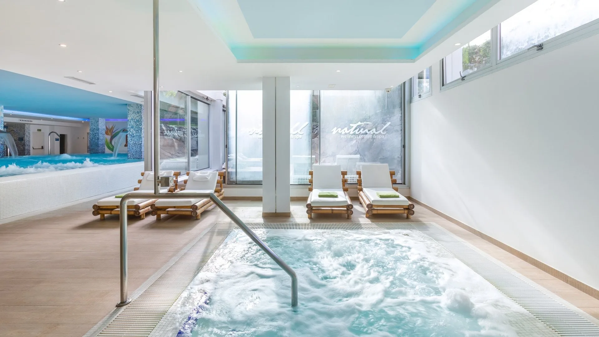 Area wellness interna con vasca idromassaggio, lettini in legno e ampie vetrate